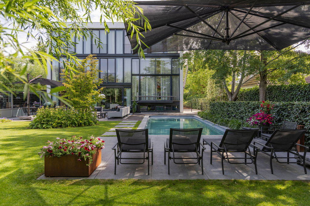 Een grote tuin met ligstoelen en een zwembad.