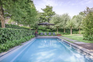 Een tuin met een groot zwembad en een aantal ligstoelen.