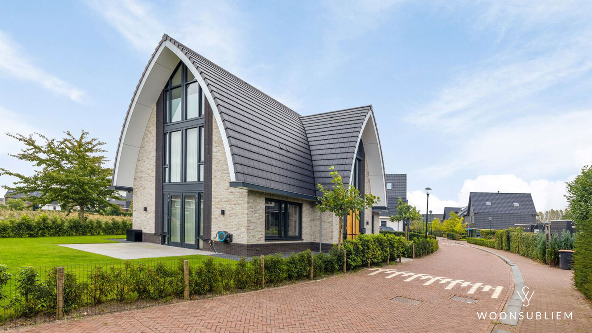 Schuin vooraanzicht van een exclusieve villa met toogkap, royale glasgevel en moderne architectuur in Blaricum.