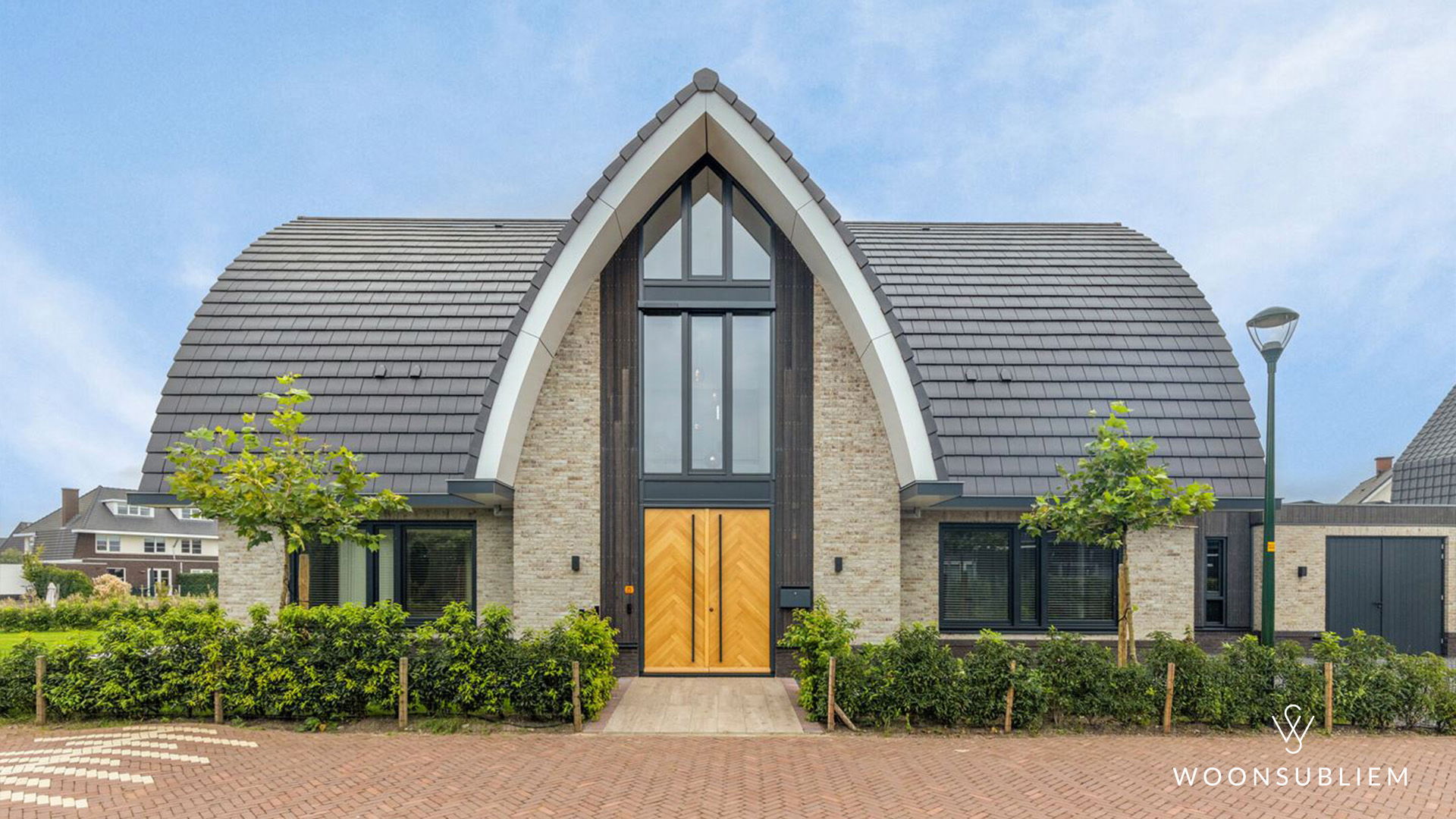 Voorzijde van een exclusieve villa met toogkap, grote glaspartij en houten entree in Blaricum.