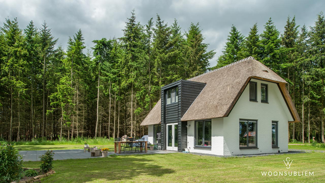 Vrijstaande rietgedekte woning in Okkenbroek met zwart houten risaliet en geïntegreerde dakkapel, ontworpen om extra ruimte te creëren op zowel de begane grond als de verdieping.