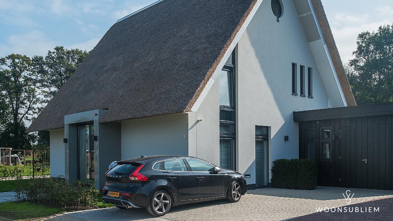 Moderne vrijstaande woning met lage risaliet, rieten kap en aangebouwde garage – ontwerp door WoonSubliem in Hengelo.