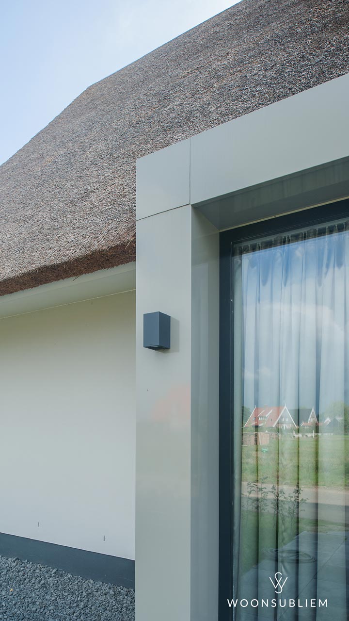 Detail van een moderne woning met rieten kap en strak vormgegeven gevel met verdiept raam, voorbeeld ter illustratie van wat een risaliet is in hedendaagse architectuur.