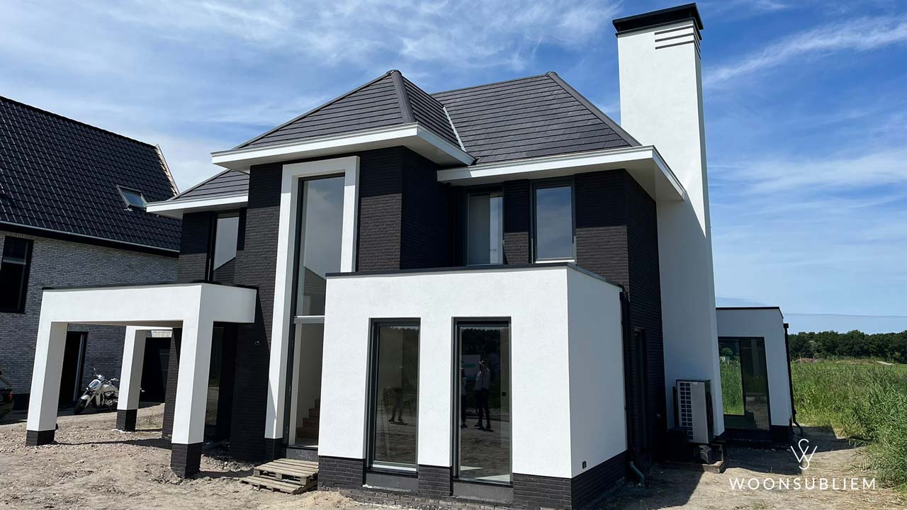 Moderne zwart-witte villa in Almere met strakke lijnen, grote raampartijen en opvallende schoorsteen, ontworpen voor een luxe en eigentijdse uitstraling.