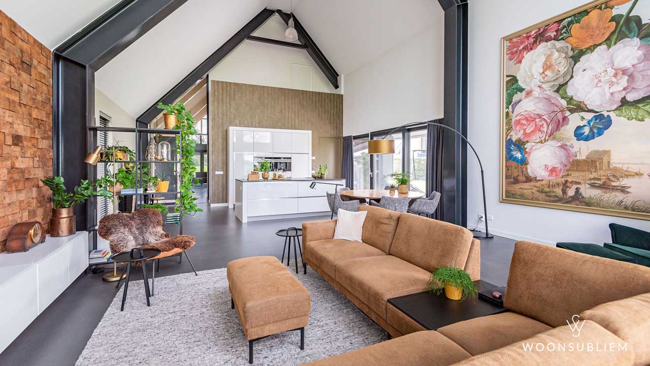 Gezellige woonkamer van schuurwoning met eiken spanten – warme inrichting met grote zithoek en open keuken.