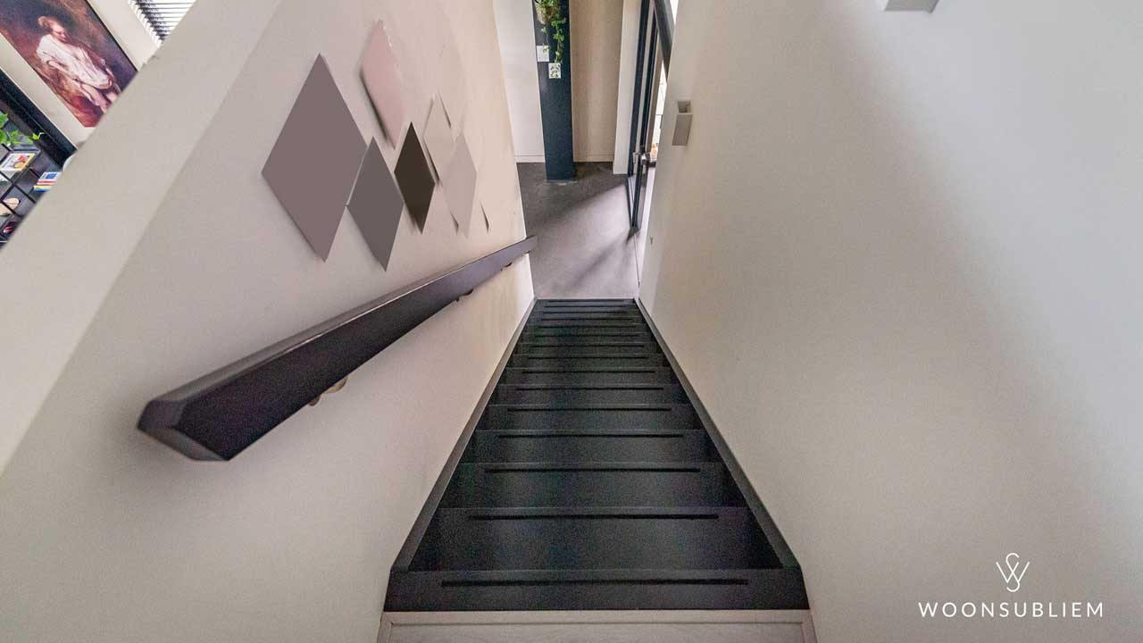 Trapopgang in moderne schuurwoning – strakke zwarte treden en minimalistische afwerking.