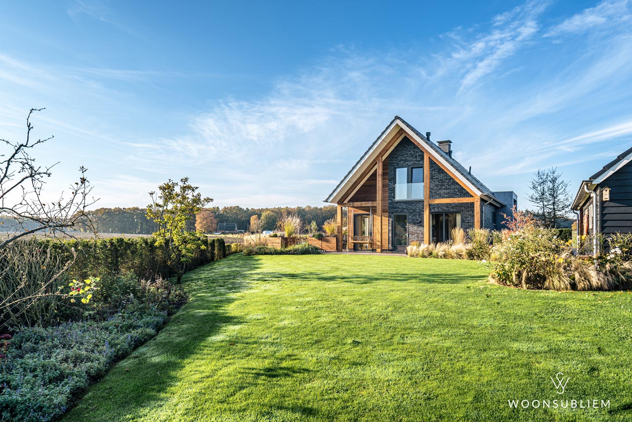 Modern-landelijke schuurwoning in Loenen ontworpen door WoonSubliem, met eiken spanten, donkere gevelstenen en royaal uitzicht op het omliggende landschap.